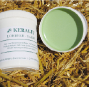 KERALIT Leberbalsam in einem weißen Behälter, geöffnet mit grünem Inhalt, auf Stroh platziert.