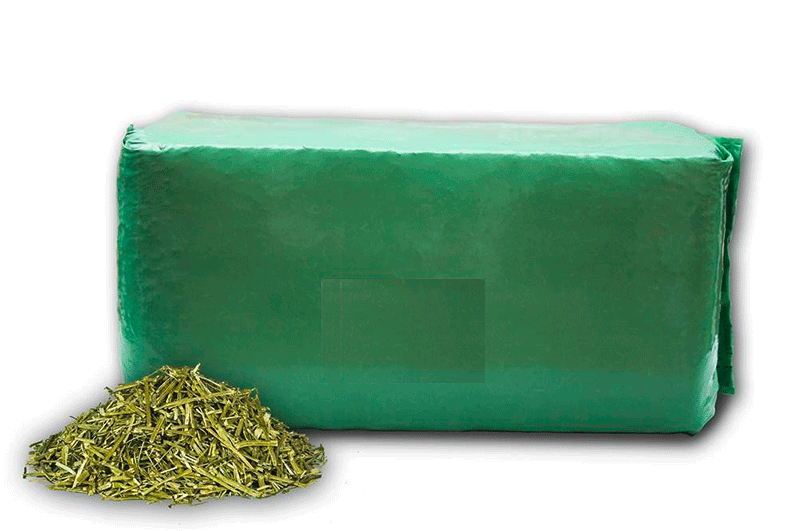 Grüne Verpackung mit einem Haufen getrockneter Kräuter daneben.