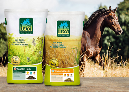 Zwei Säcke mit Pferdefutter von LEXA, einer mit Karotten Mash und der andere mit Vitalmix Classic, im Vordergrund, im Hintergrund ein Pferd auf der Weide.