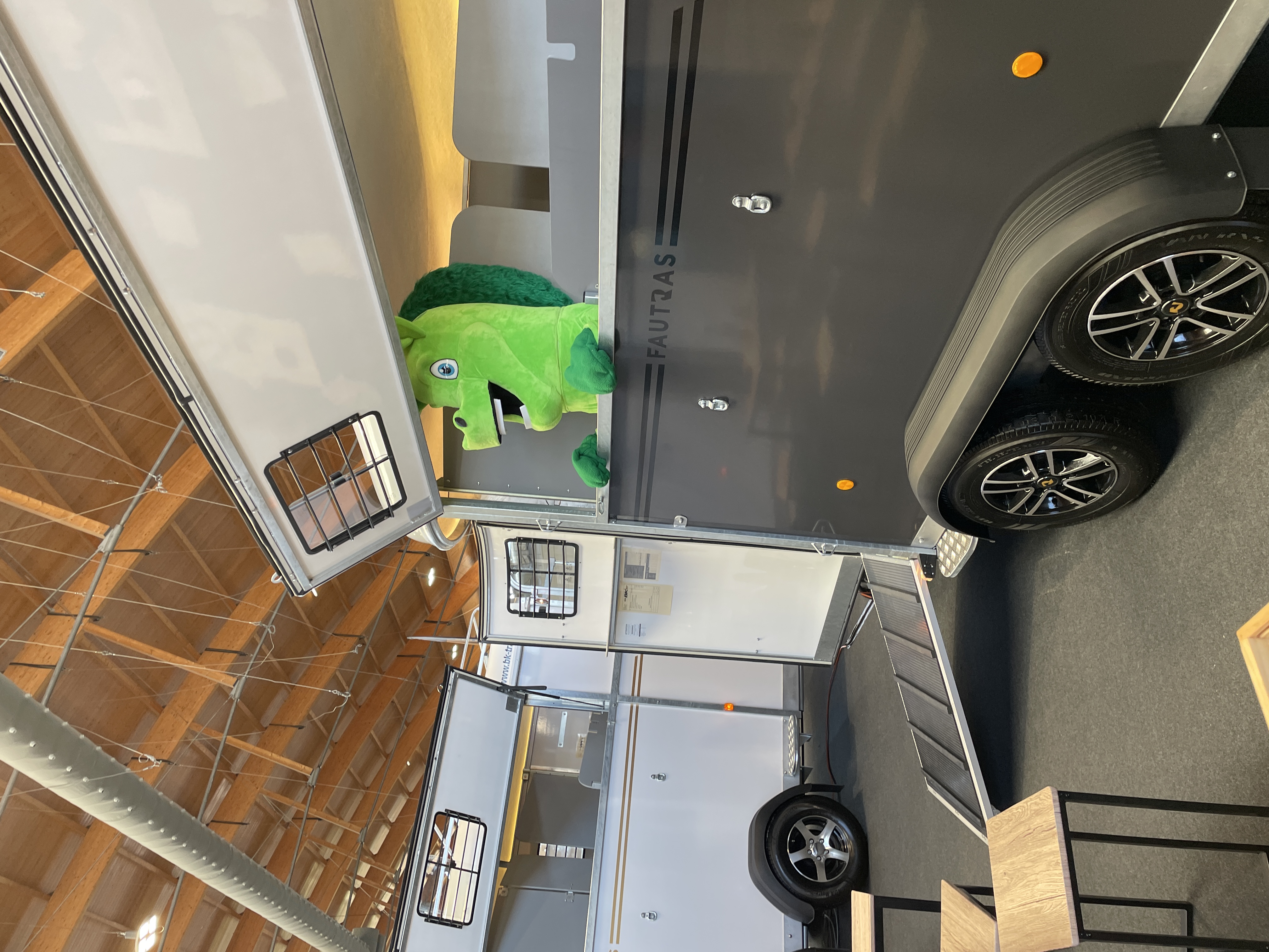 Ein grünes Maskottchen in einem Wohnwagen, der auf einem Ausstellungsstand steht.